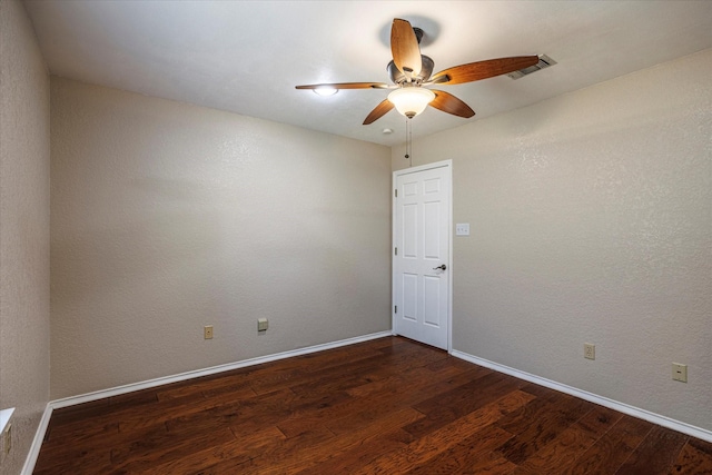 spare room with baseboards, visible vents, dark wood finished floors, and a ceiling fan