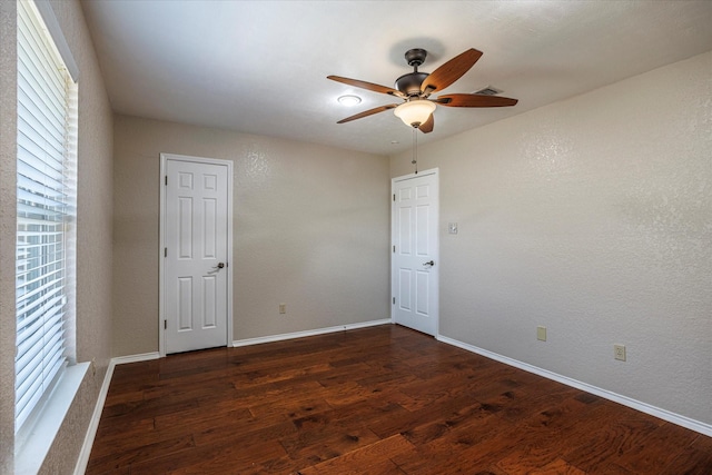 empty room with dark wood-style floors, plenty of natural light, baseboards, and ceiling fan