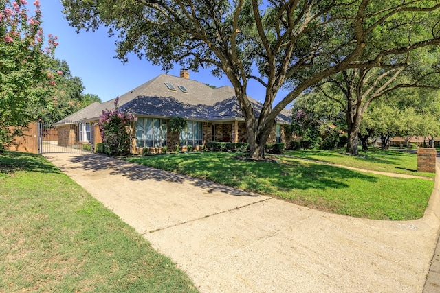 ranch-style home with concrete driveway, a front lawn, a chimney, and a gate