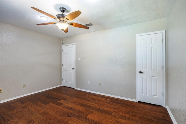 empty room with dark wood-style floors, baseboards, visible vents, and ceiling fan