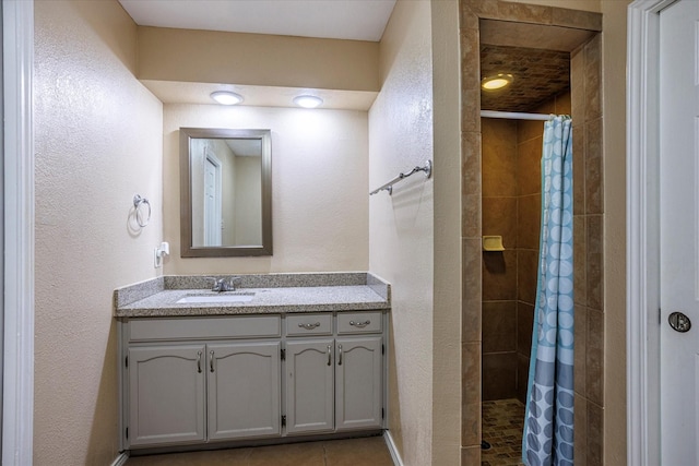 full bathroom featuring a stall shower, tile patterned flooring, a textured wall, and vanity