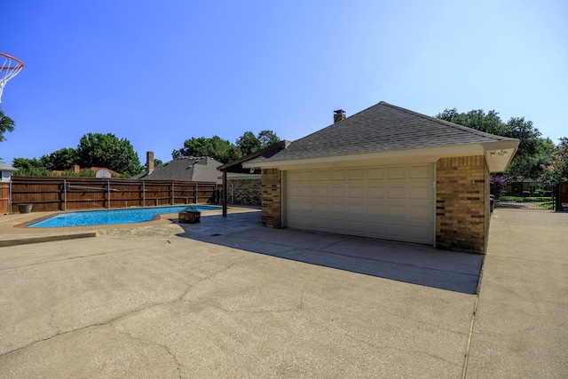 exterior space featuring a garage, brick siding, a shingled roof, and fence