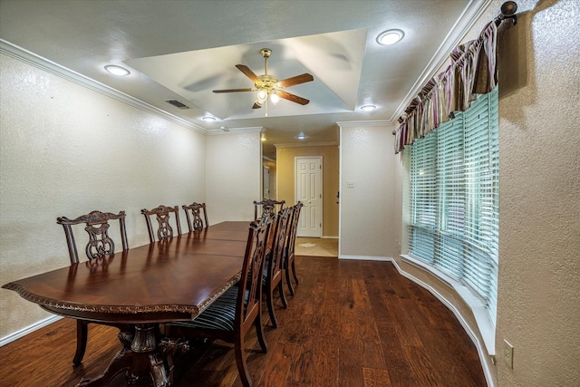 dining space with visible vents, a raised ceiling, dark wood-style flooring, and ornamental molding