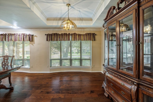 dining area with ornamental molding, a raised ceiling, and dark wood-style flooring