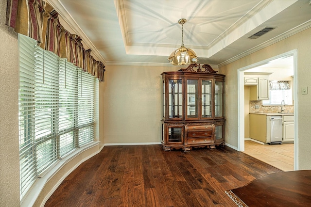 unfurnished dining area featuring a chandelier, a sink, wood finished floors, ornamental molding, and a raised ceiling