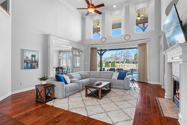 living room with wood-type flooring, baseboards, arched walkways, and a tile fireplace