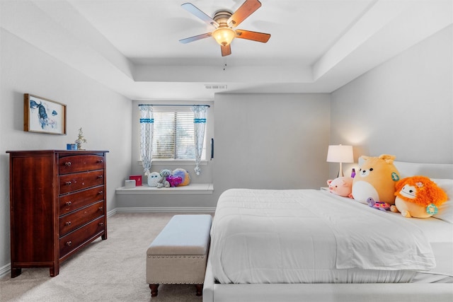 bedroom with light carpet, baseboards, visible vents, ceiling fan, and a tray ceiling