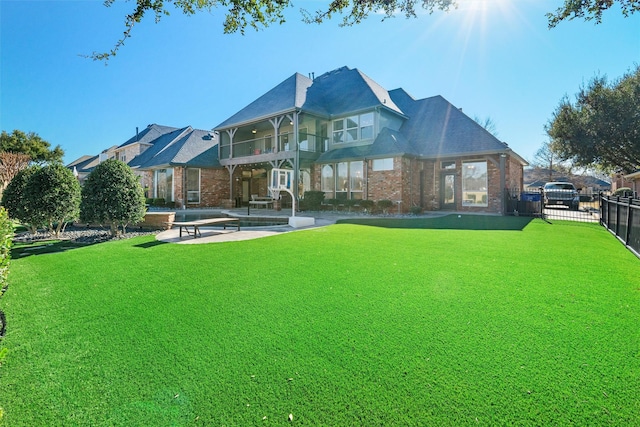 rear view of property featuring brick siding, a lawn, and fence