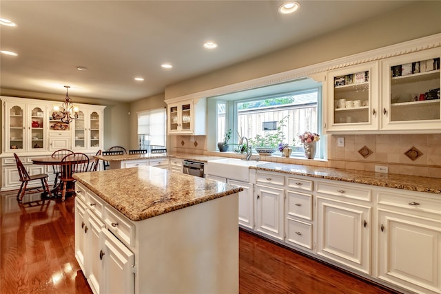 kitchen with glass insert cabinets, a center island, white cabinets, and hanging light fixtures