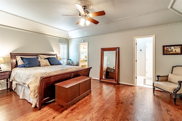 bedroom featuring a ceiling fan, connected bathroom, vaulted ceiling, wood finished floors, and baseboards