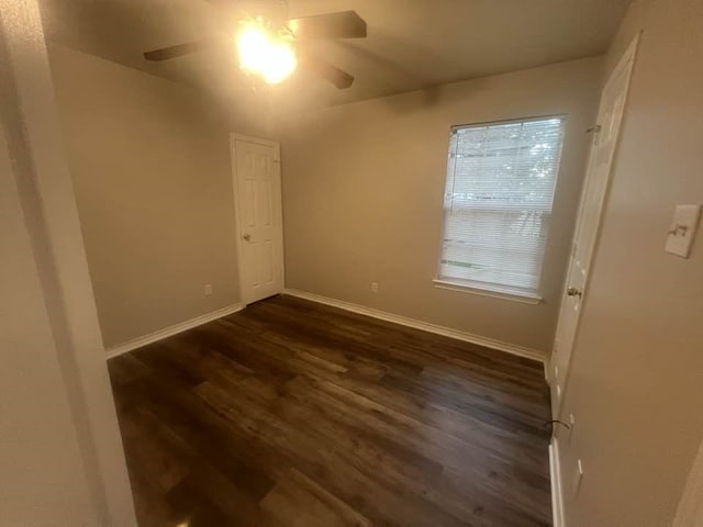 spare room featuring ceiling fan, dark wood-type flooring, and baseboards