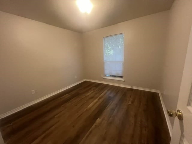 unfurnished room featuring dark wood-style flooring and baseboards