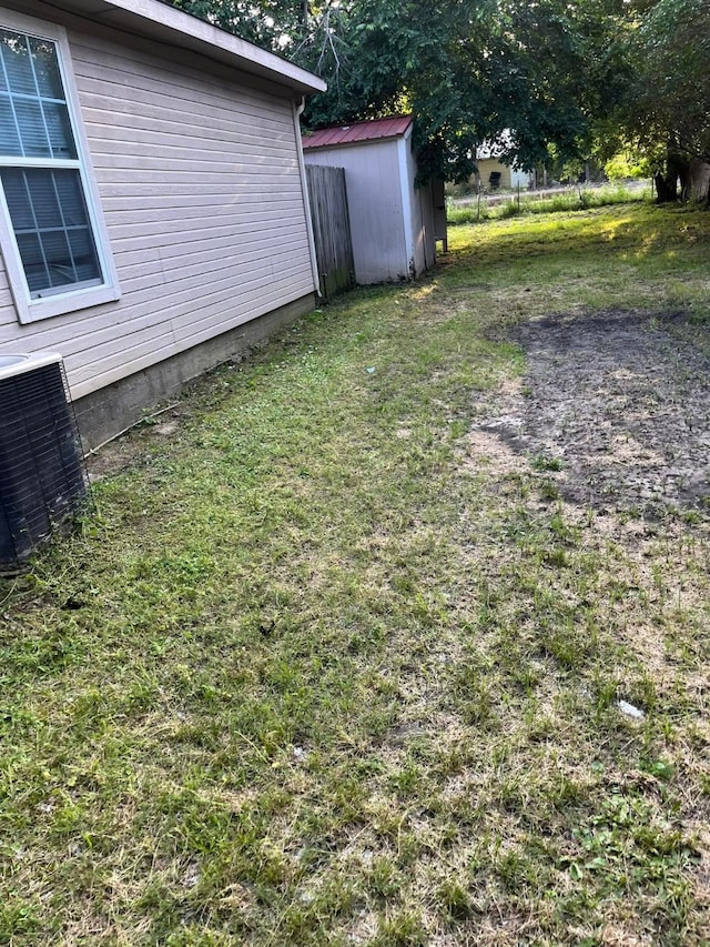 view of yard with central air condition unit, a storage unit, and an outbuilding