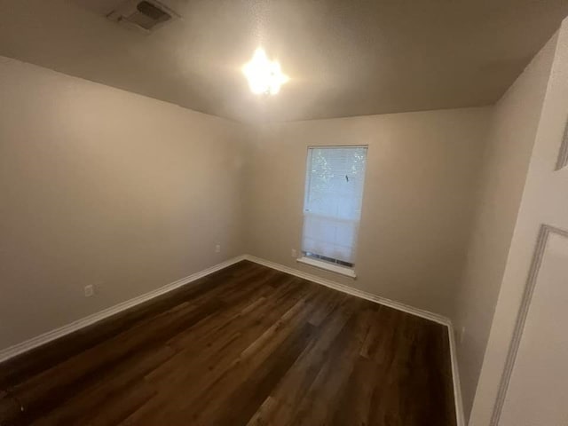 spare room with dark wood finished floors and baseboards