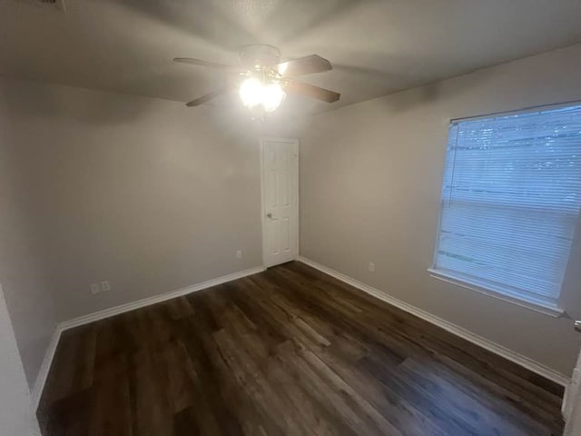 spare room featuring dark wood-style floors, baseboards, and a ceiling fan