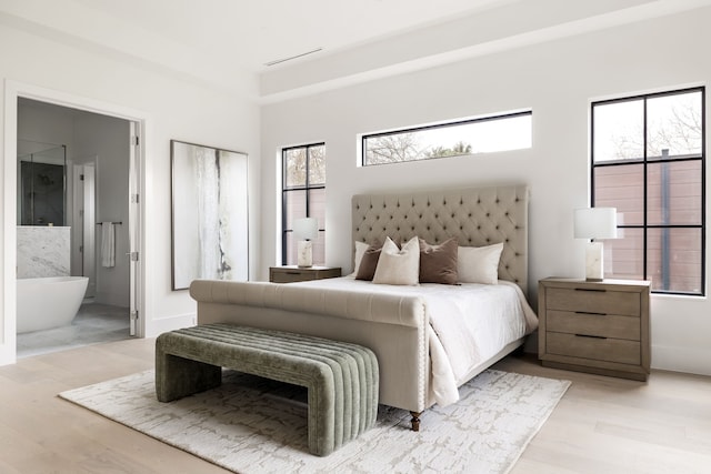 bedroom featuring visible vents, baseboards, light wood-style flooring, and ensuite bath