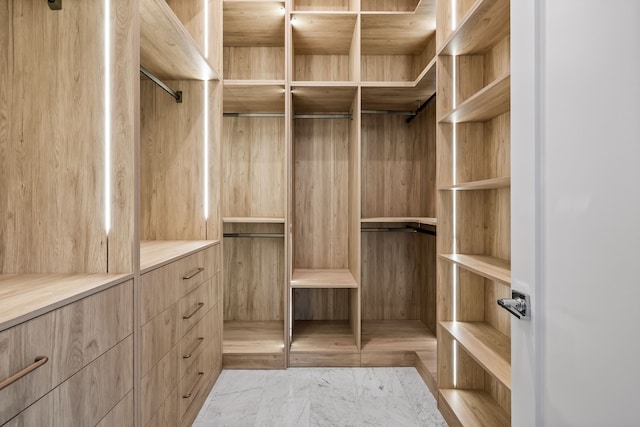 walk in closet featuring marble finish floor