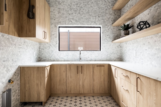 kitchen featuring modern cabinets, light countertops, light floors, open shelves, and a sink