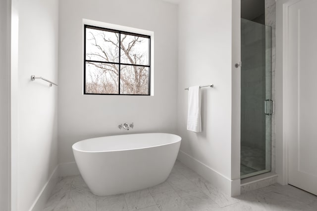 bathroom featuring a freestanding bath, marble finish floor, a stall shower, and baseboards