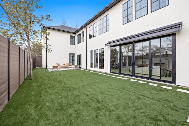 rear view of house with stucco siding, a fenced backyard, an outdoor living space, a patio area, and a yard