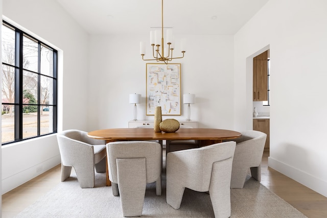 dining area with baseboards, light wood-style flooring, and a notable chandelier