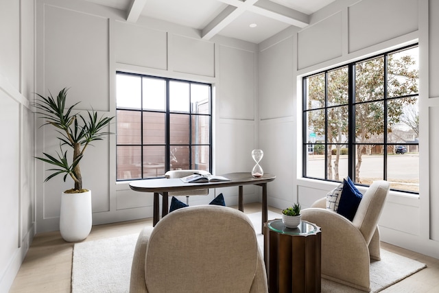 office space featuring coffered ceiling, light wood-style floors, a decorative wall, and beam ceiling