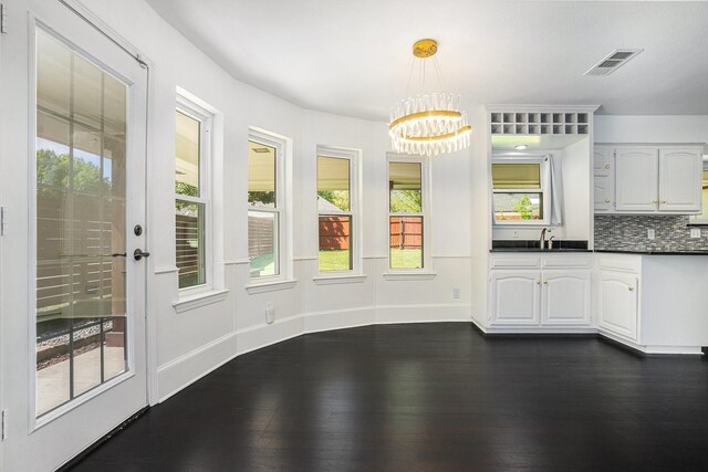 unfurnished dining area with dark wood-style flooring, baseboards, an inviting chandelier, visible vents, and a sink