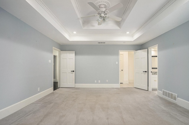 empty room with ornamental molding, light carpet, a ceiling fan, visible vents, and a raised ceiling