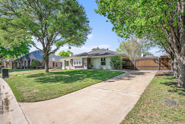 ranch-style house featuring a chimney, concrete driveway, brick siding, a front lawn, and a gate