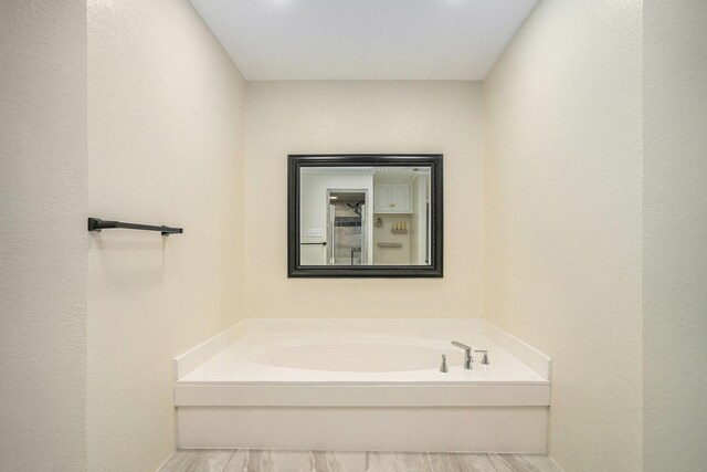 bathroom with a bath and wood finished floors