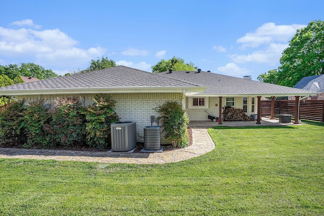 rear view of property with a lawn, fence, a patio, central air condition unit, and brick siding