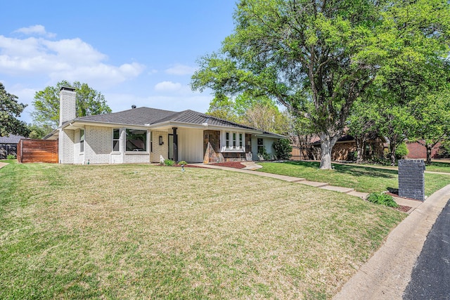 ranch-style home featuring brick siding, a front lawn, fence, and a chimney