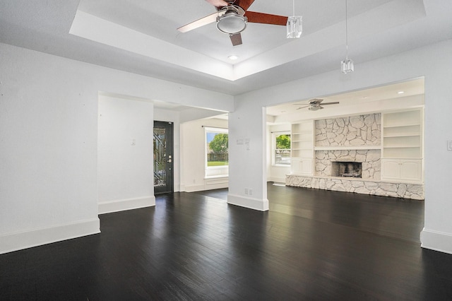 unfurnished living room with ceiling fan, a raised ceiling, wood finished floors, and baseboards