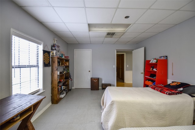 bedroom featuring baseboards, visible vents, and a drop ceiling