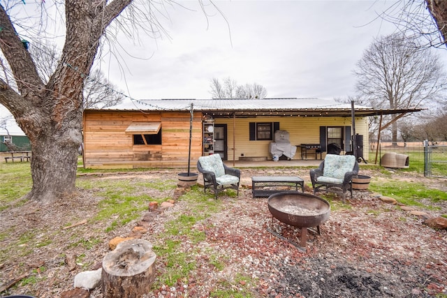 back of house featuring metal roof and a fire pit