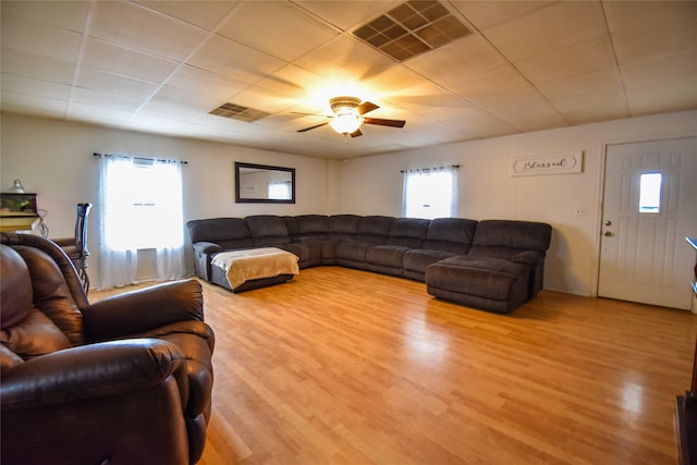 living area featuring a paneled ceiling, wood finished floors, visible vents, and a ceiling fan