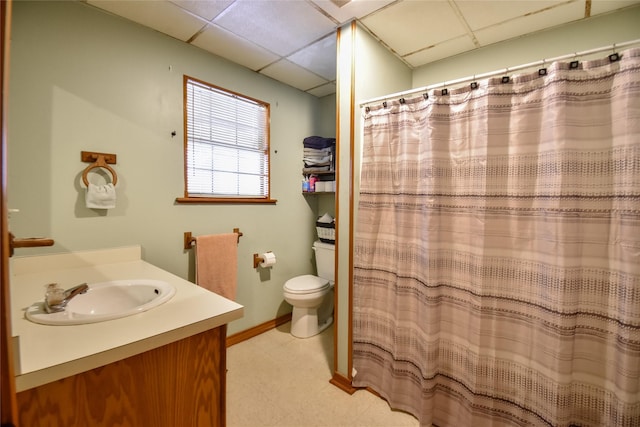 bathroom featuring baseboards, a drop ceiling, toilet, a shower with curtain, and vanity