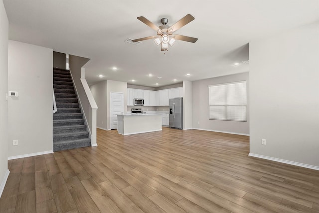 unfurnished living room with ceiling fan, recessed lighting, visible vents, stairway, and light wood-type flooring