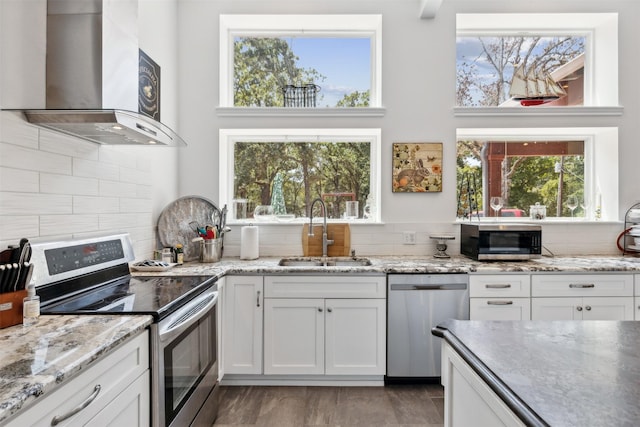 kitchen with white cabinets, decorative backsplash, stainless steel appliances, a sink, and exhaust hood