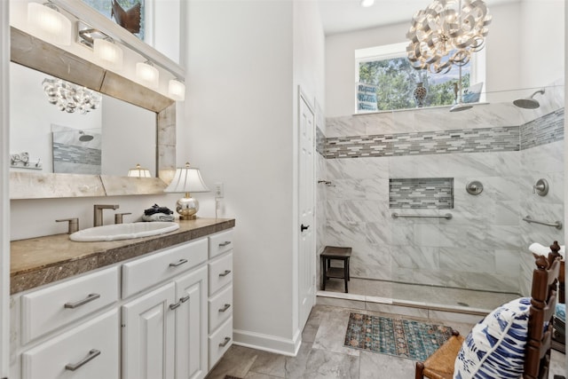 full bath featuring a chandelier, vanity, baseboards, and walk in shower