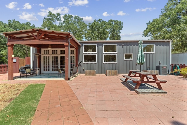 rear view of house with board and batten siding, french doors, fence, and a patio