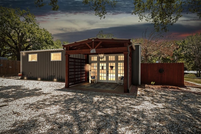 view of outbuilding featuring french doors and fence