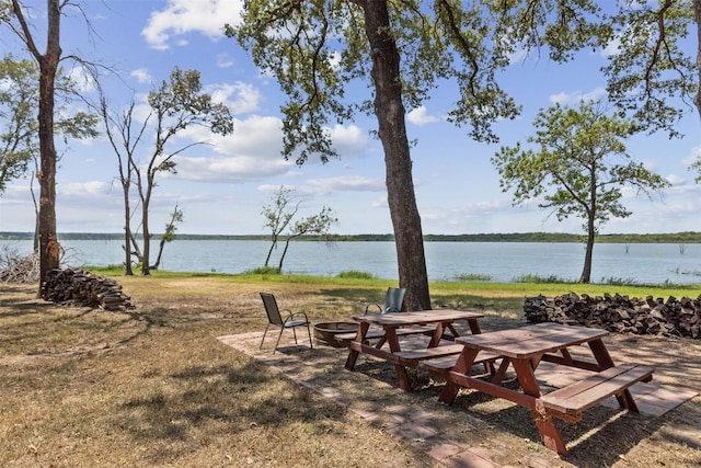 view of community with a yard, an outdoor fire pit, and a water view