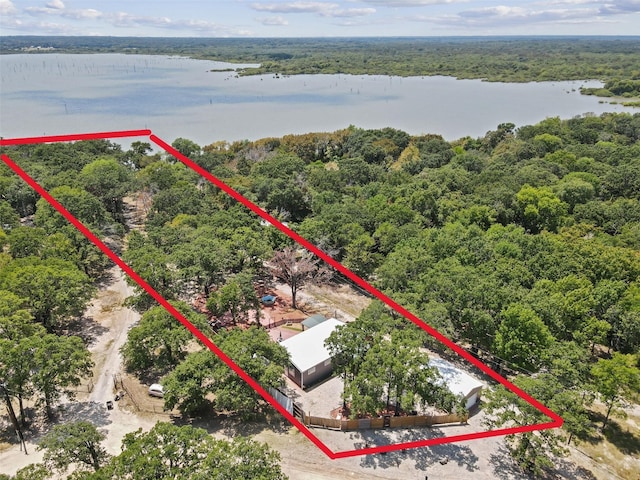 birds eye view of property with a water view and a wooded view