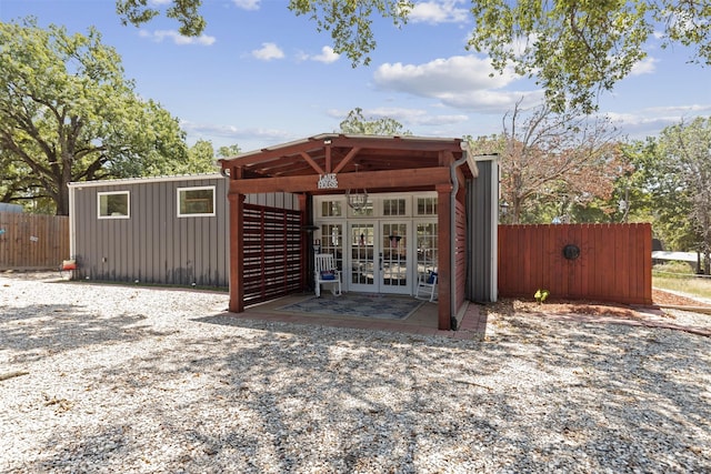 view of outbuilding featuring french doors and fence