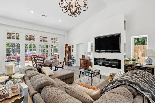 living area with visible vents, a chandelier, a glass covered fireplace, high vaulted ceiling, and recessed lighting