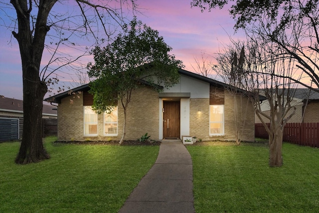 mid-century home with fence, a front lawn, and brick siding