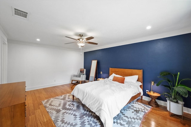 bedroom with recessed lighting, wood finished floors, visible vents, baseboards, and ornamental molding