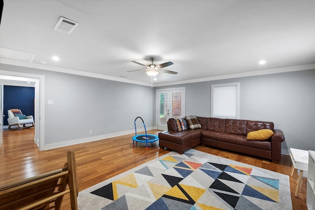 living room with visible vents, crown molding, light wood-style flooring, and baseboards