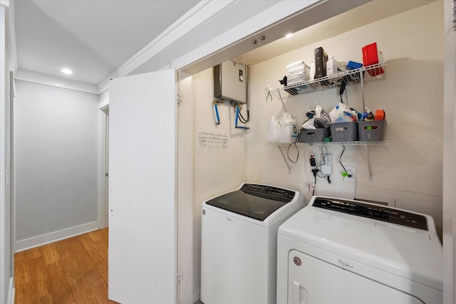 clothes washing area with recessed lighting, laundry area, water heater, light wood finished floors, and washing machine and clothes dryer